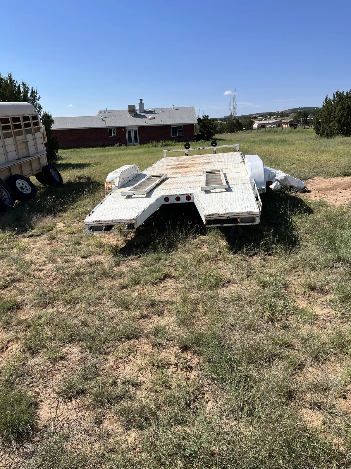 A car-hauler trailer in weathered paint with rust across the deck.