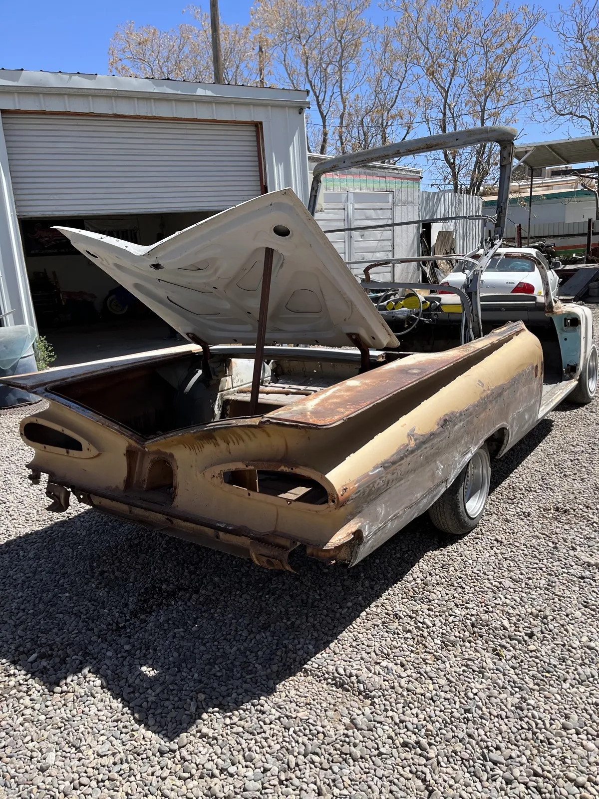 A 1959 Chevrolet El Camino in tan paint with rust through the deck.
