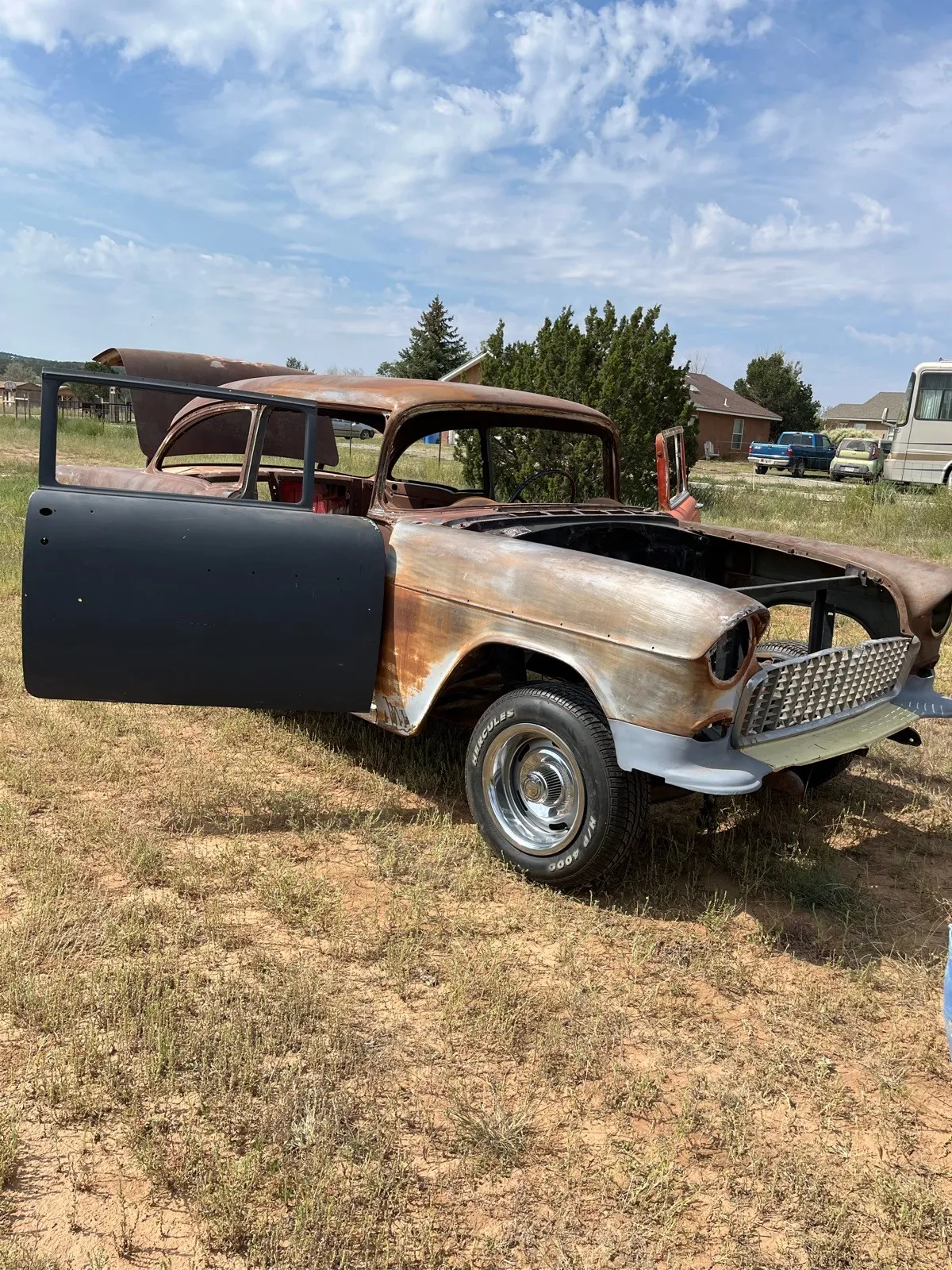 A 1955 Chevrolet in worn paint, filler and surface rust, photographed before blasting.